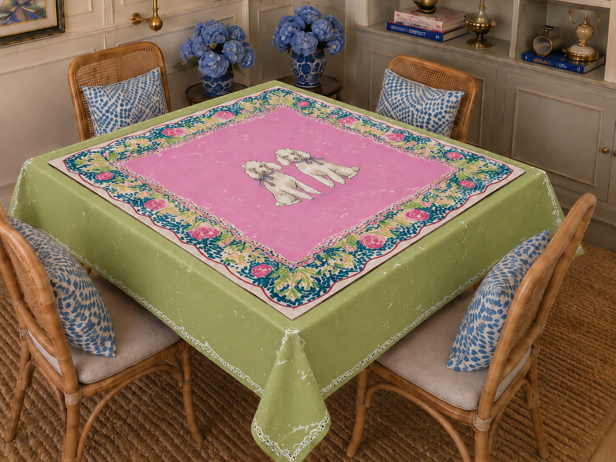 Jean Doesn't Have Favorites tablecloth — green ground with pink center, two white poodles and navy floral border, styled in a dining room. NOLI JUNE coordinating tablecloth.