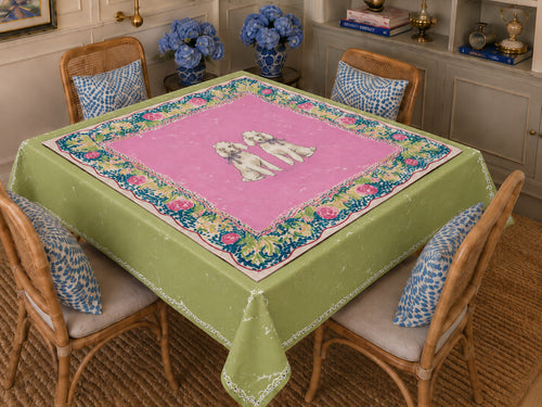Jean Doesn't Have Favorites tablecloth — green ground with pink center, two white poodles and navy floral border, styled in a dining room. NOLI JUNE coordinating tablecloth.
